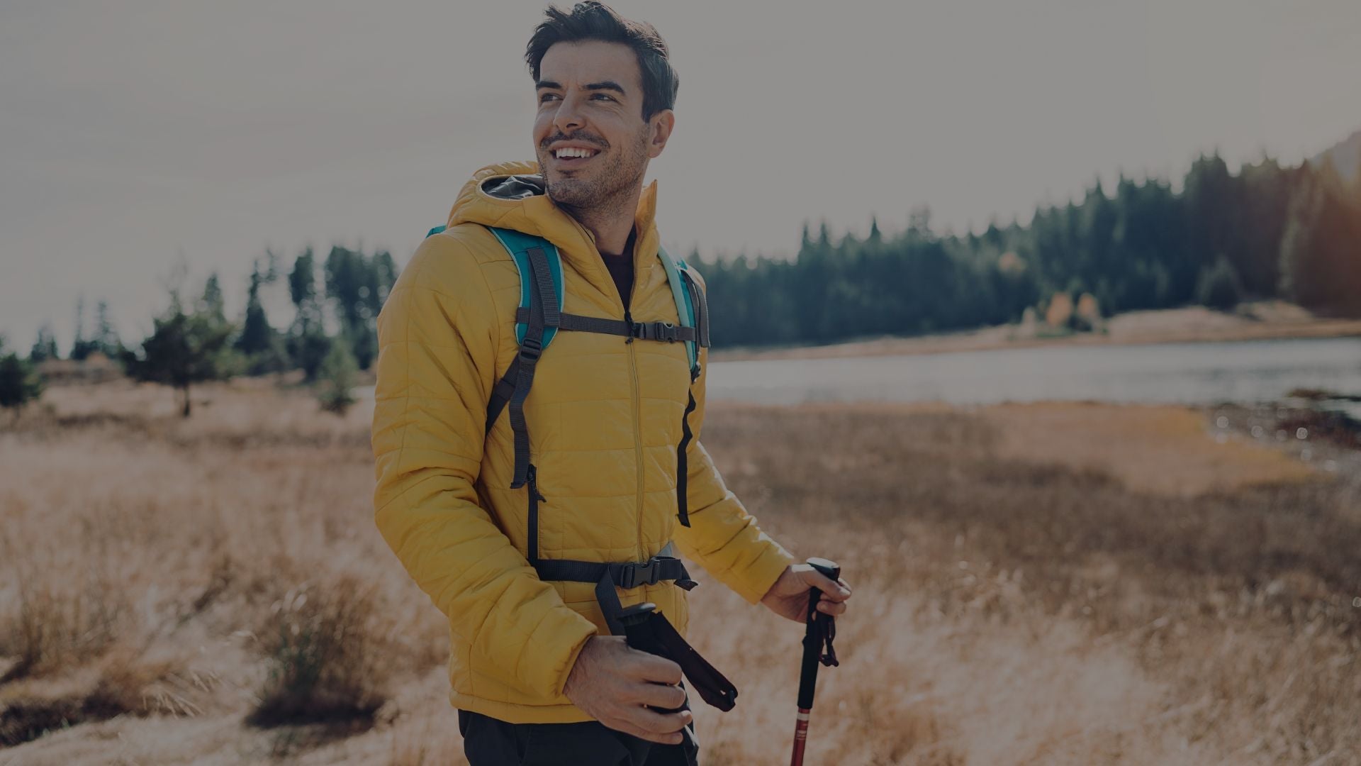 Man in a yellow jacket with a backpack hiking in a natural landscape